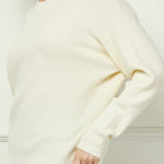 Woman wearing a white sweater against a light background
