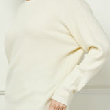 Woman wearing a white sweater against a light background
