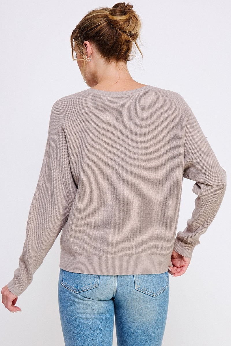 Person wearing a beige sweater and blue jeans on a white background