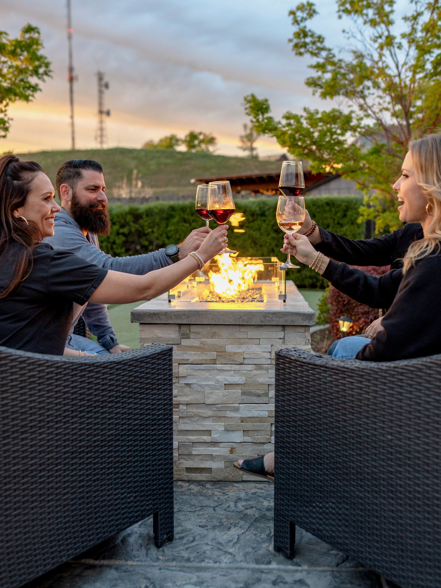 Friends sipping wine by the fire in the backyard