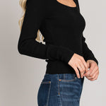 Woman wearing a black long-sleeve top and blue jeans on a gray background