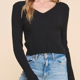 Woman wearing a black long-sleeve top and blue jeans on a beige background