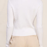 Woman wearing a white long-sleeve top and beige pants against a beige background