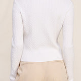 Woman wearing a white long-sleeve top and beige pants against a beige background