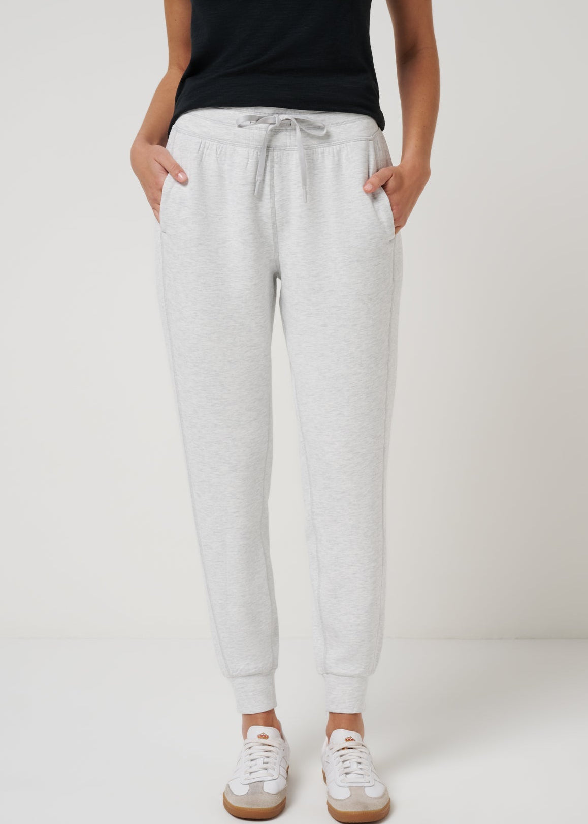 Person wearing gray sweatpants on a plain background