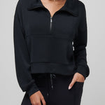 Woman wearing a black half-zip sweatshirt against a gray background