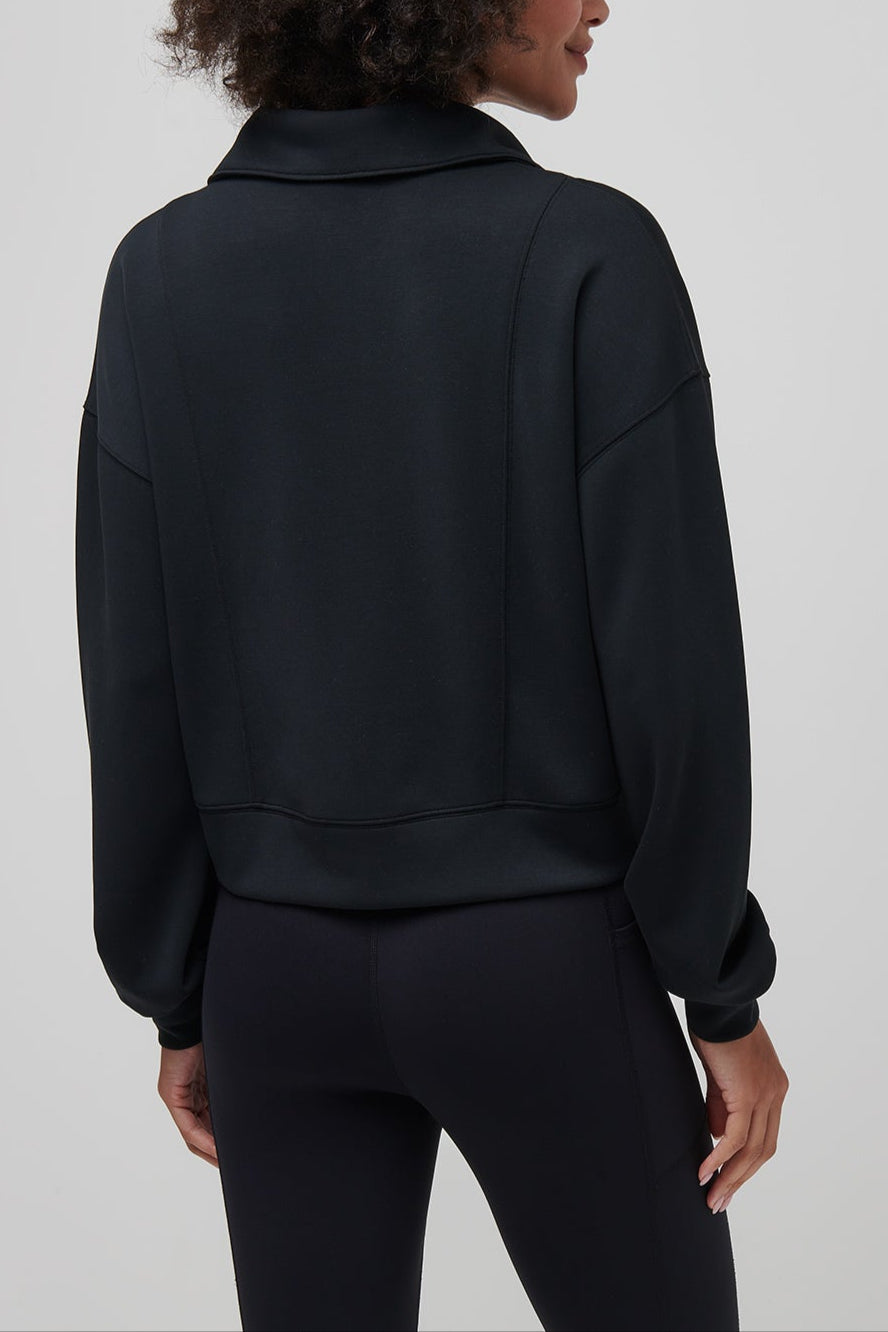 Person wearing a black jacket and pants on a plain background