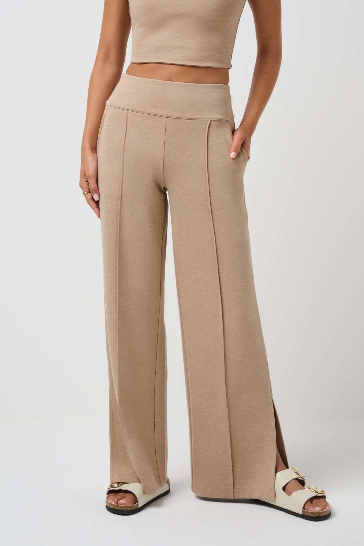 Beige high-waisted pants worn by a person on a white background