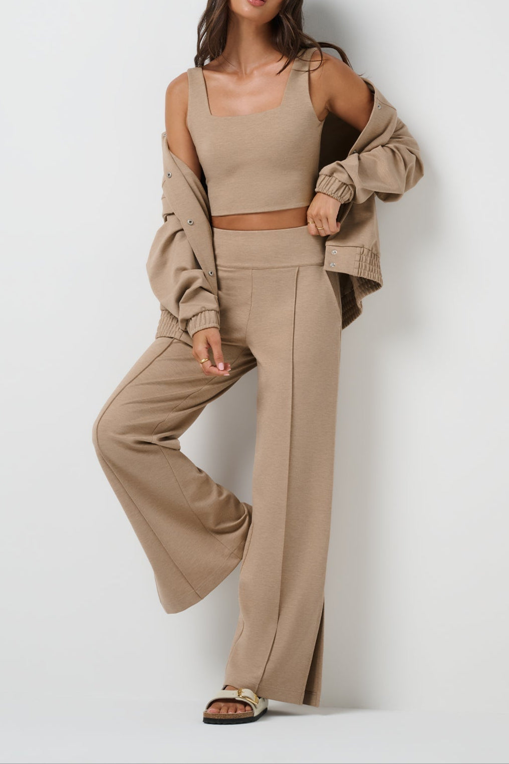 Woman wearing a beige outfit with a matching jacket against a white background