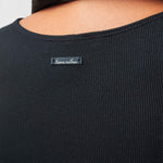Black ribbed sweater with a brand label on a neutral background