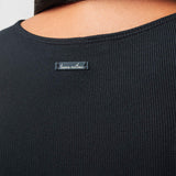 Black ribbed sweater with a brand label on a neutral background