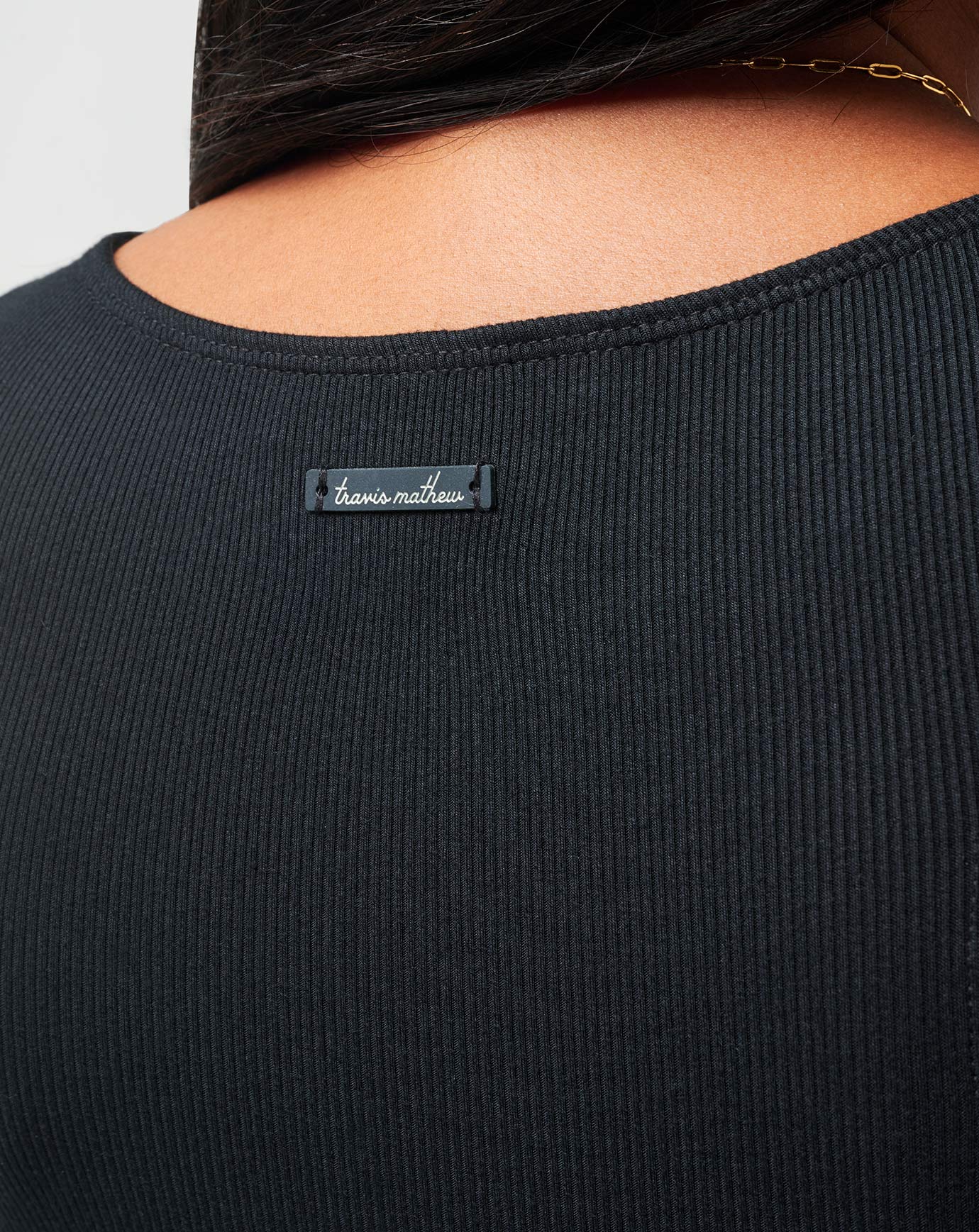 Black ribbed sweater with a brand label on a neutral background