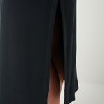 Black dress with a slit on a plain background