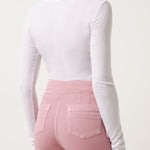 Woman wearing a white long-sleeve top and pink pants on a white background
