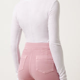 Woman wearing a white long-sleeve top and pink pants on a white background