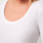 Close-up of a person wearing a white long-sleeve shirt with a plain background