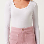 Woman wearing a white long-sleeve top and pink pants on a white background