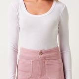 Woman wearing a white long-sleeve top and pink pants on a white background