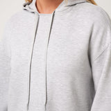 Close-up of a person wearing a light gray hoodie with a neutral background