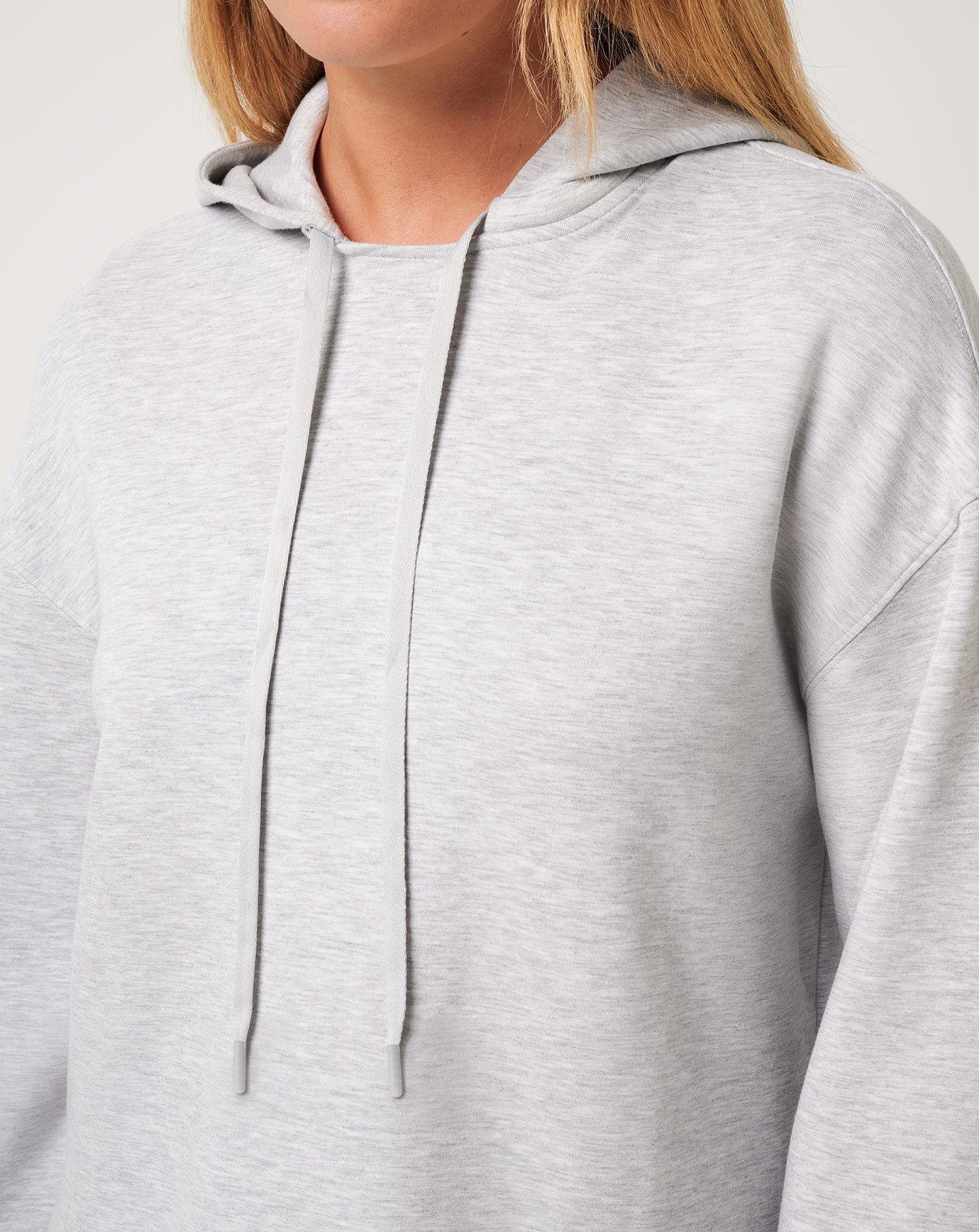 Close-up of a person wearing a light gray hoodie with a neutral background