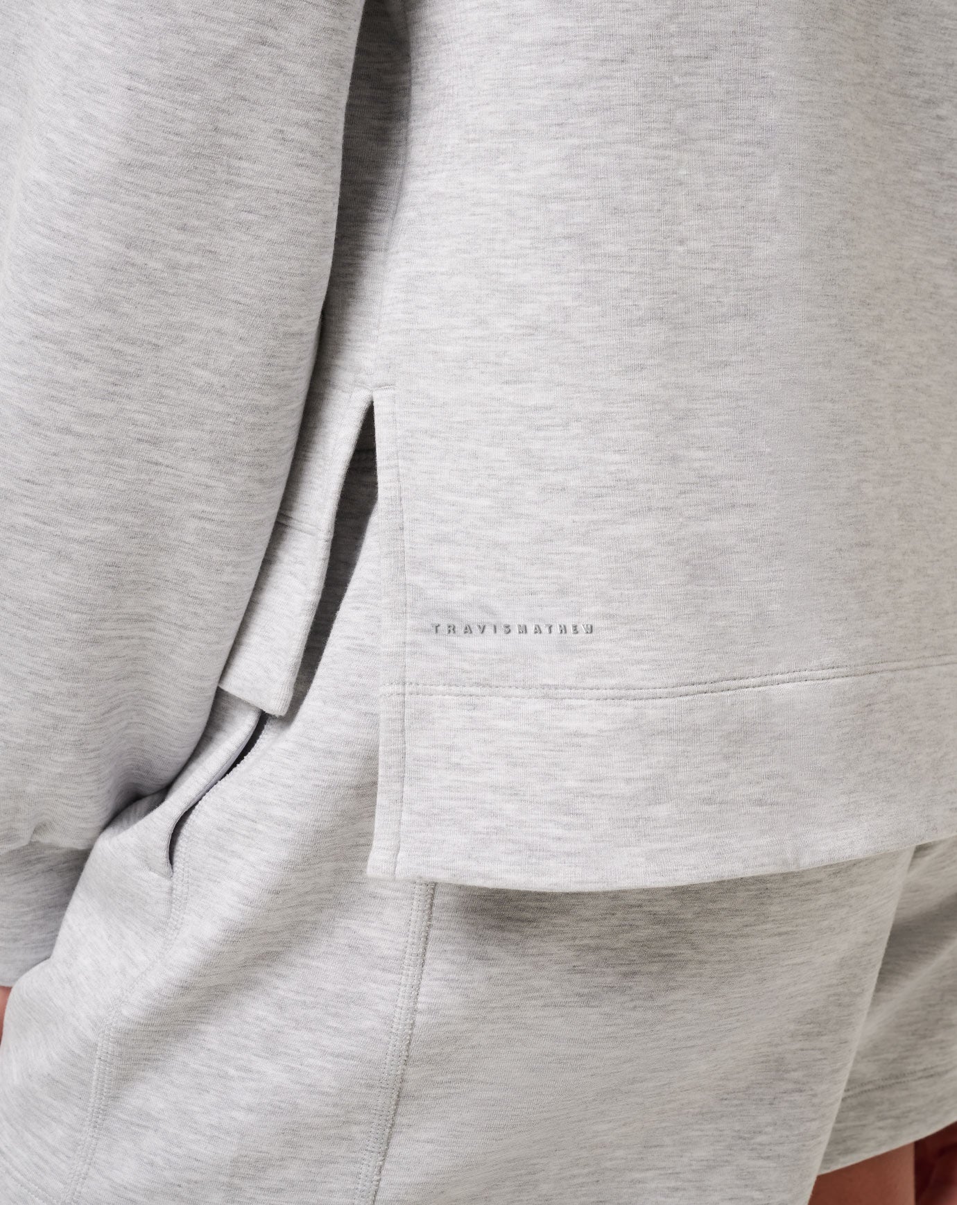 Close-up of a gray suit jacket with a brand logo on the chest pocket.