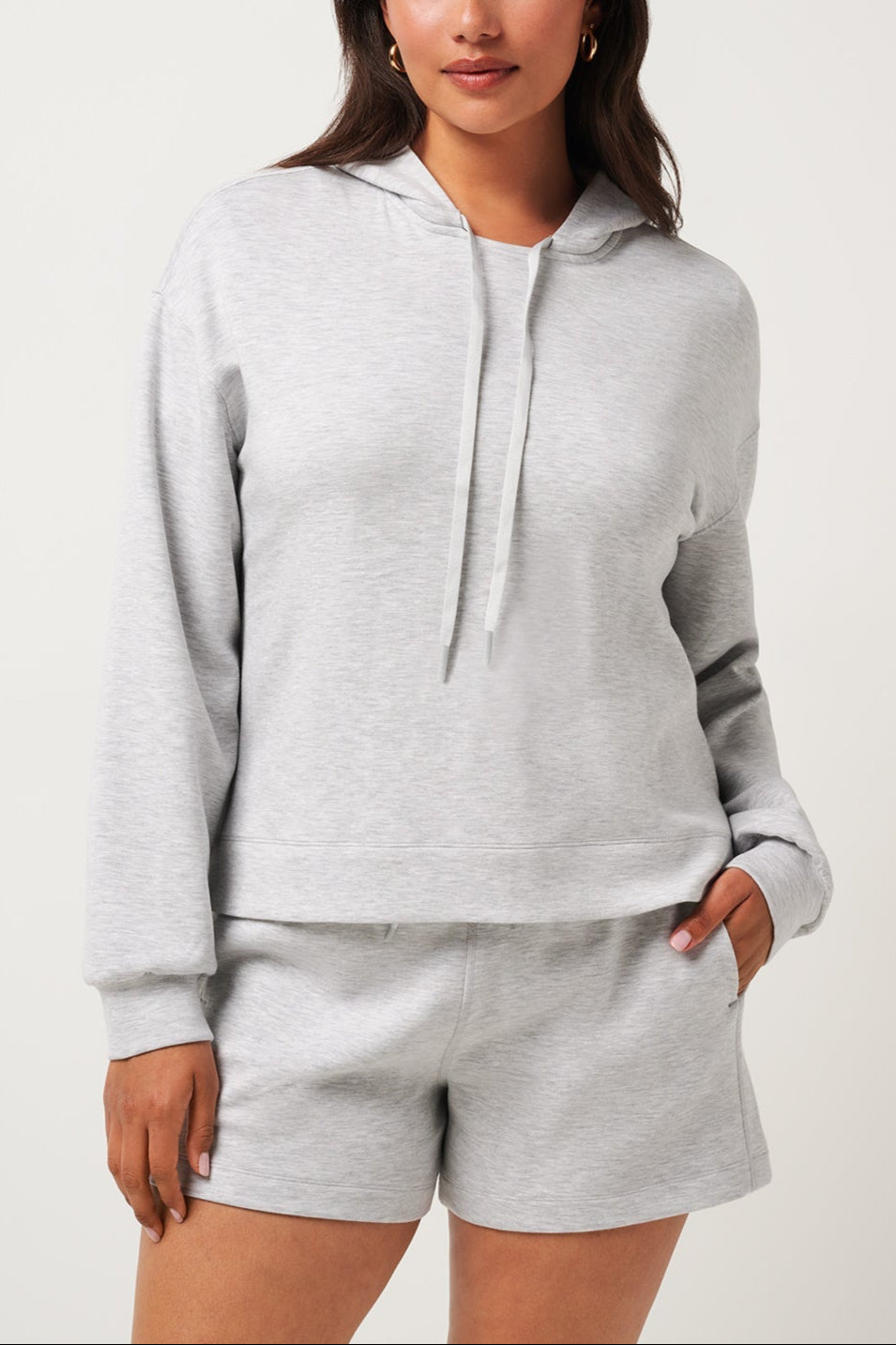 Woman wearing a gray hoodie and shorts set on a white background