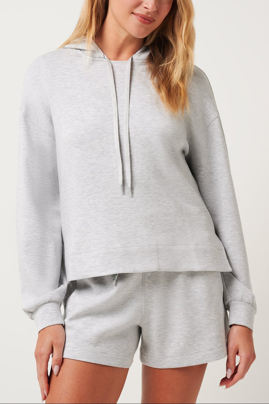 Woman wearing a gray hoodie and shorts set on a white background