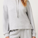 Woman wearing a gray hoodie and shorts set on a white background