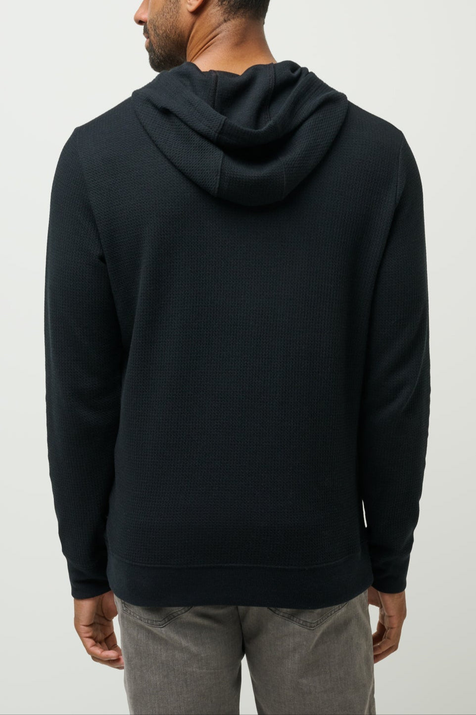 Man wearing a black hoodie from behind on a light gray background