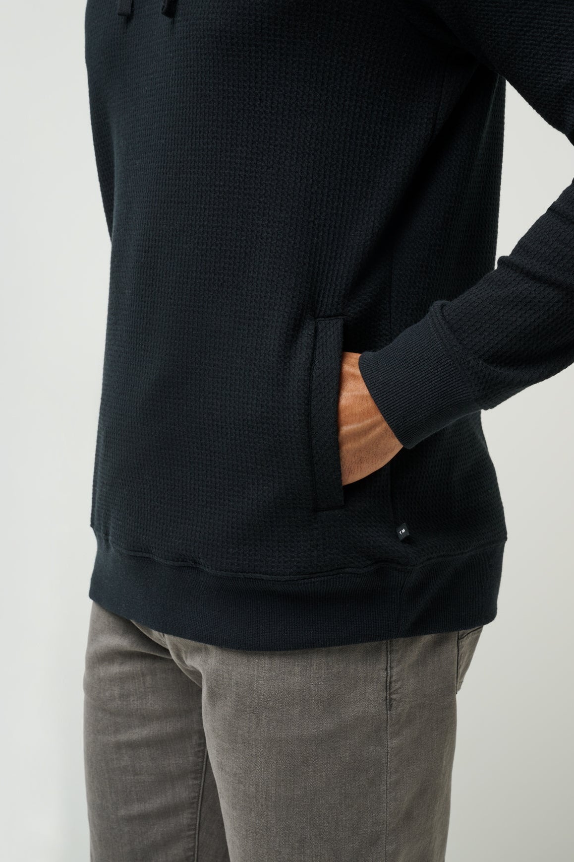 Person wearing a black long-sleeve shirt and gray pants on a light gray background