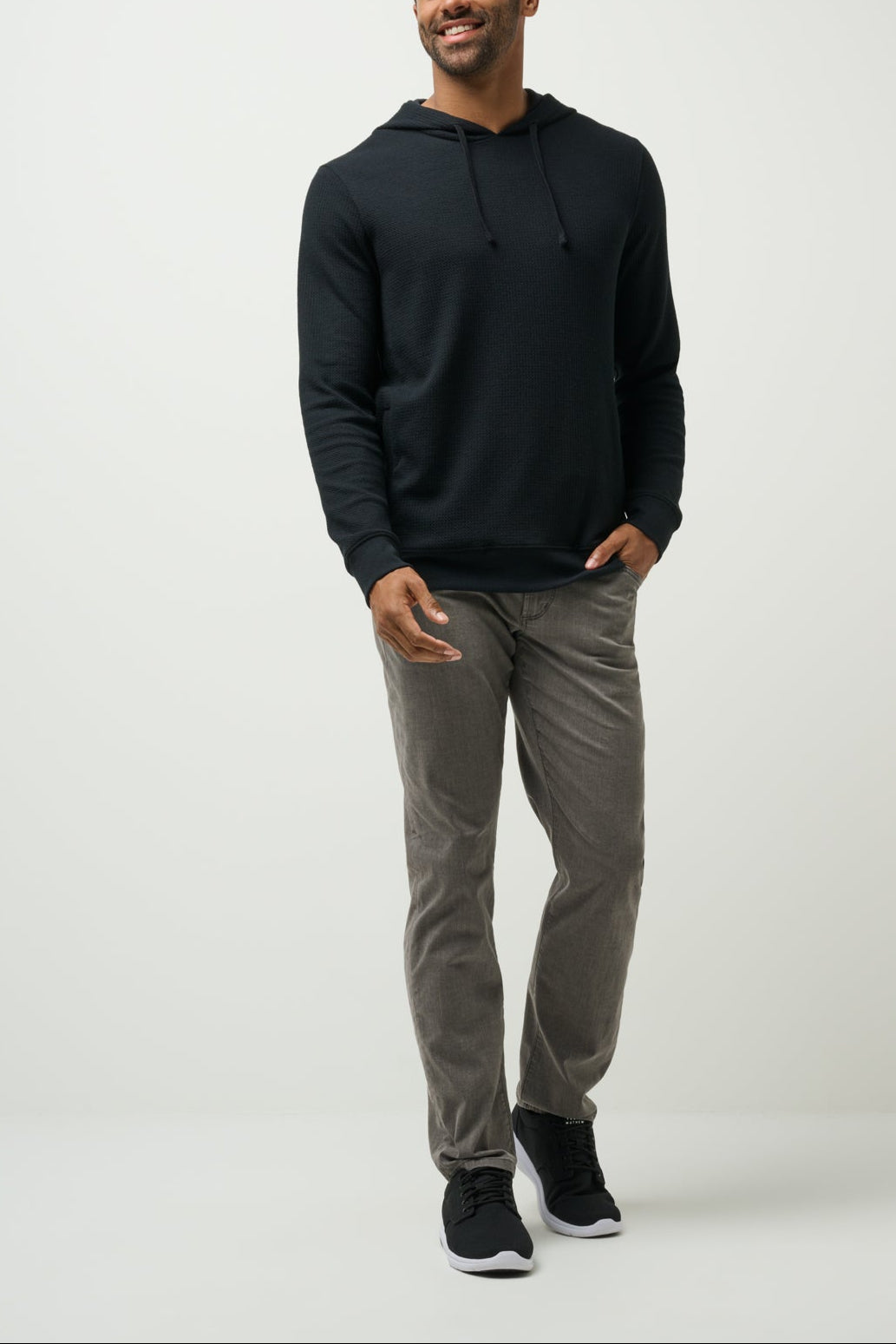Man wearing a black hoodie and gray pants on a white background
