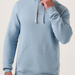 Man wearing a light blue hoodie against a plain background