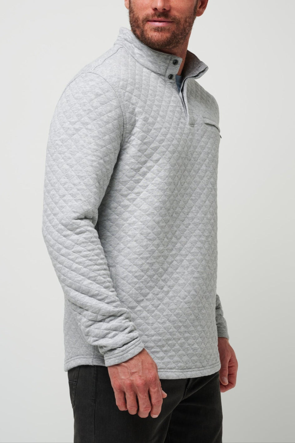 Man wearing a light gray quilted pullover against a plain background