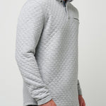 Man wearing a light gray quilted pullover against a plain background
