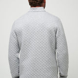 Man wearing a gray quilted jacket on a plain background