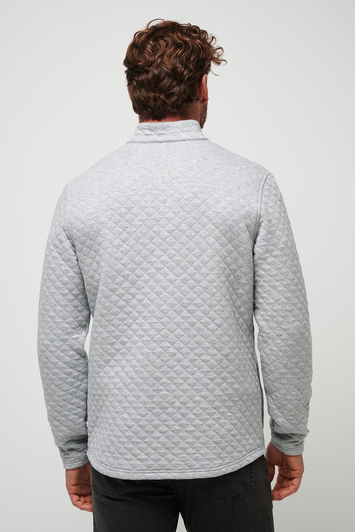 Man wearing a gray quilted jacket on a plain background
