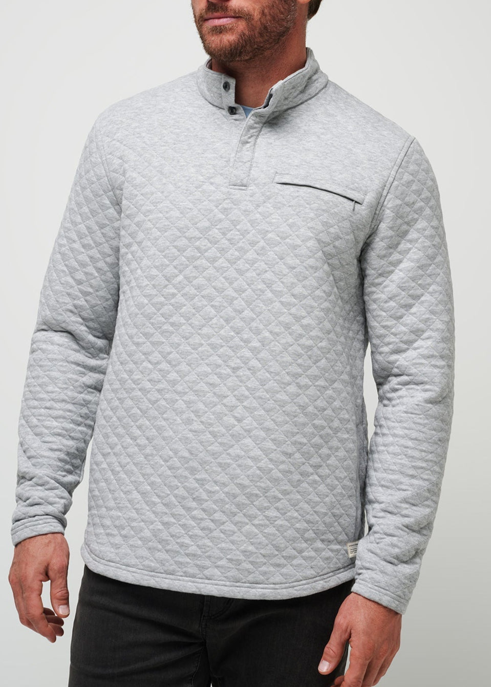 Man wearing a gray quilted pullover against a light gray background