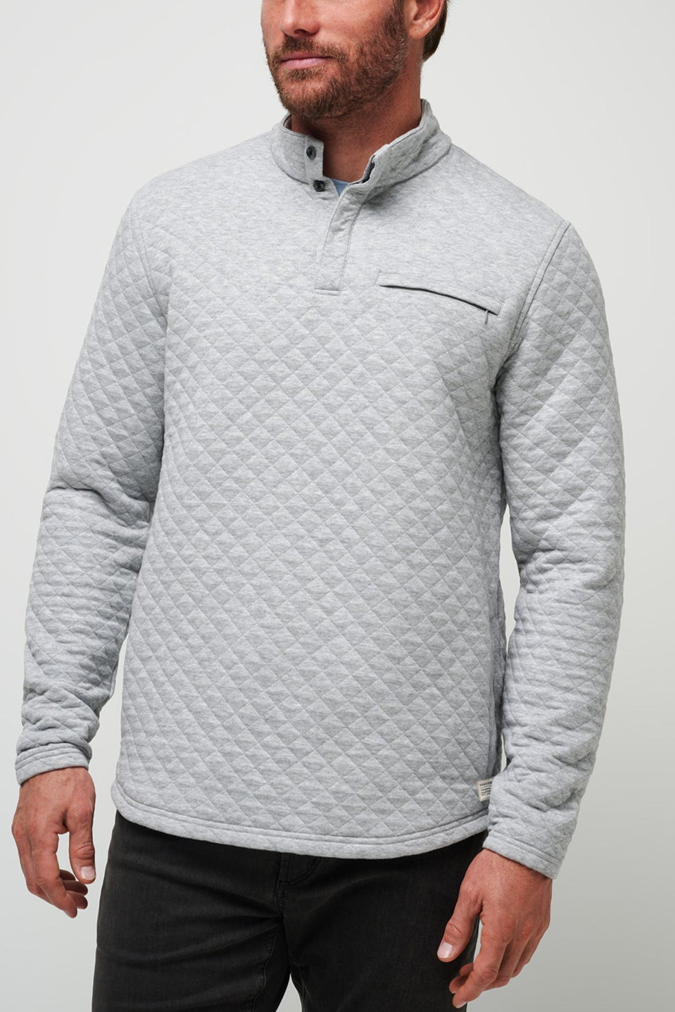 Man wearing a gray quilted pullover against a light gray background