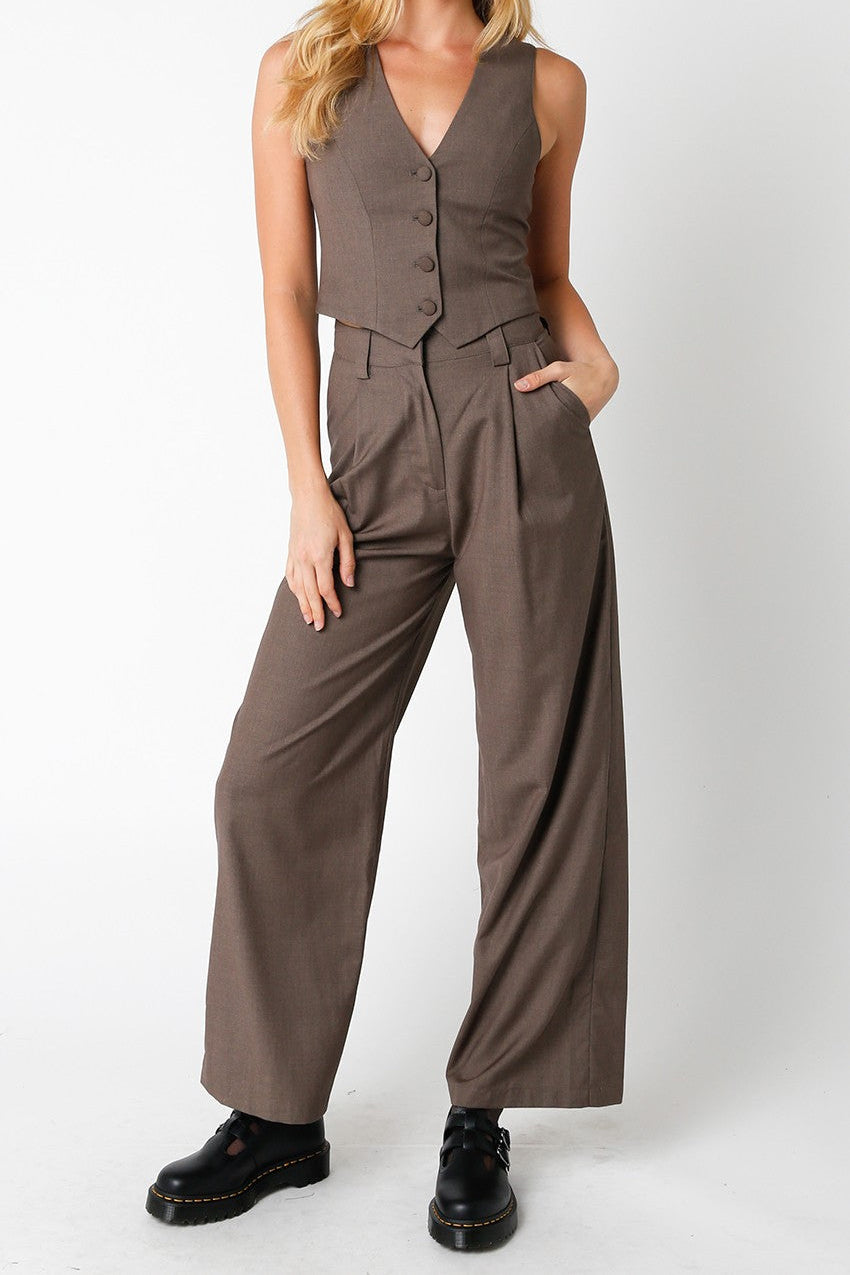 Woman wearing a brown jumpsuit with a vest on a white background