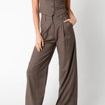Woman wearing a brown jumpsuit with a vest on a white background
