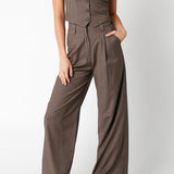 Woman wearing a brown jumpsuit with a vest on a white background