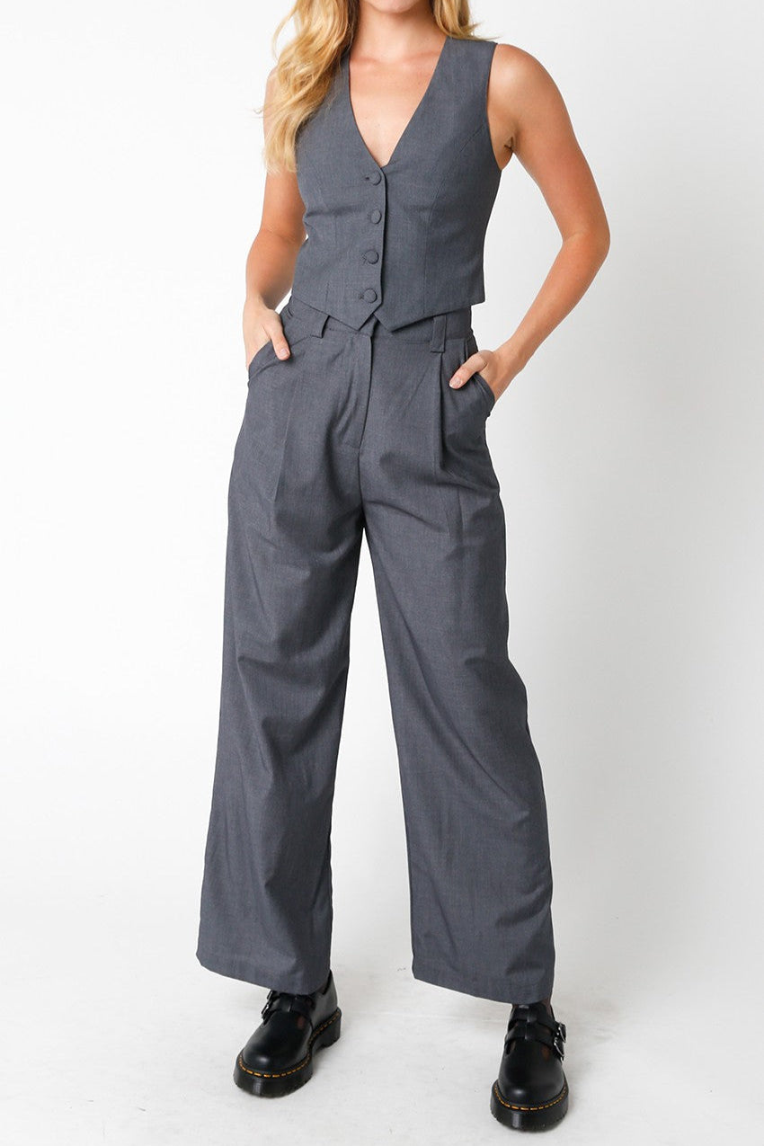 Woman wearing a gray jumpsuit with a vest on a white background