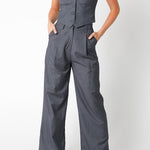 Woman wearing a gray jumpsuit with a vest on a white background
