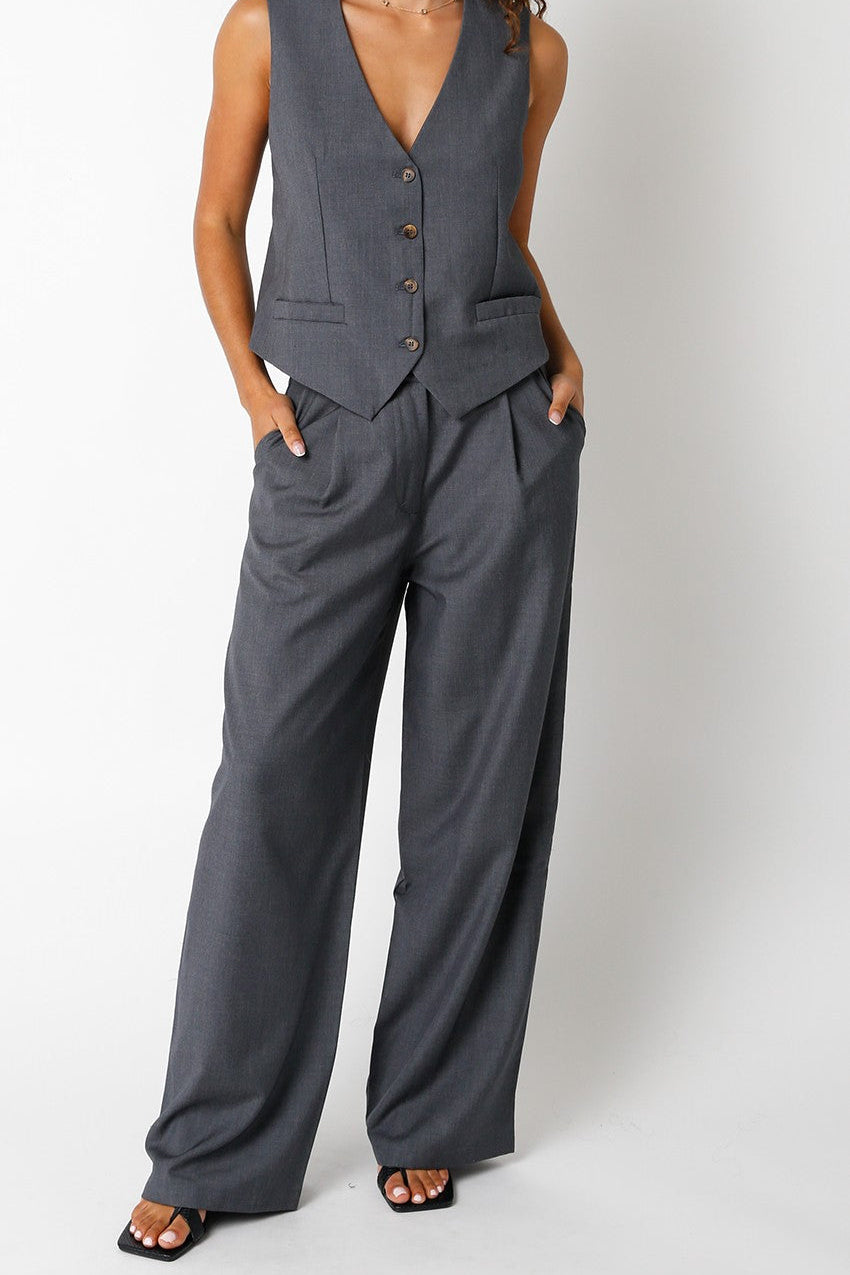 Woman wearing a gray vest and wide-leg pants on a white background