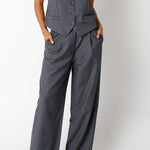 Woman wearing a gray vest and wide-leg pants on a white background