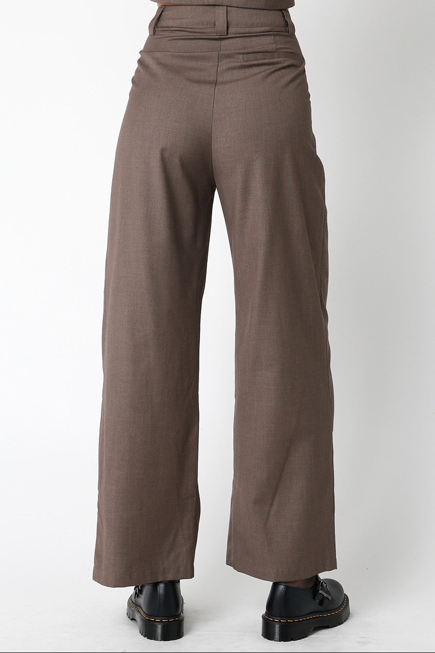 Brown pants worn with a suit jacket on a white background