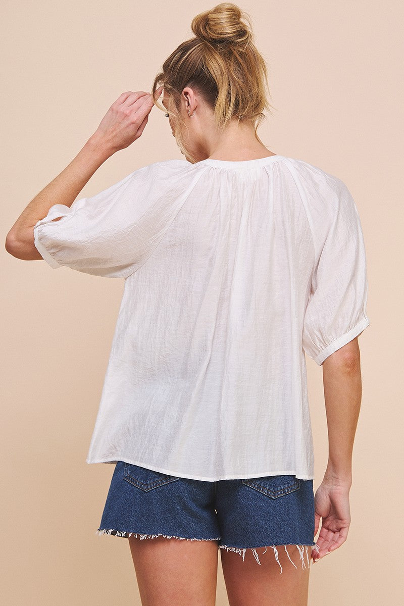 Woman wearing a white blouse and denim shorts on a beige background