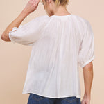 Woman wearing a white blouse and denim shorts on a beige background