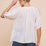 Woman wearing a white blouse and denim shorts on a beige background