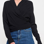 Woman wearing a black long-sleeve top and blue denim shorts on a white background